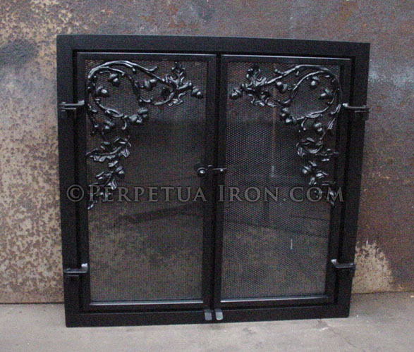 Black rectangular fireplace screen with vine pattern inset design in front of glass fire screen.