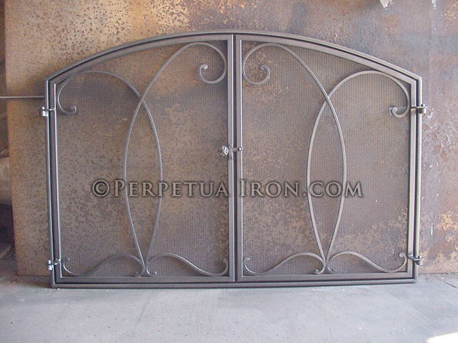 Ornamental iron fireplace screen with mesh doors.