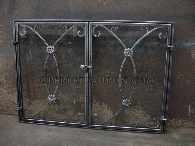 Wrought iron fireplace screen or fire screen with scroll work and rosettes. Glass spark screen with two doors and clasp.