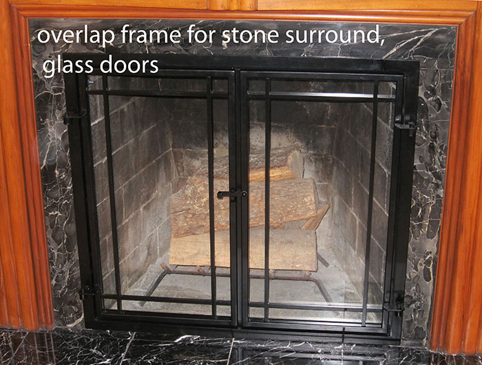 Photo of installed glass fireplace door. The rame is an overlap style with a black paitina and craftsman style muntin design.