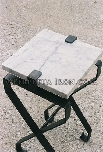 Close up view of forged steel table with marble slab top.
