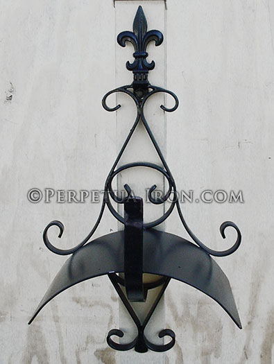 An ornate wrought iron wrought iron hose holder with fleur de lis.