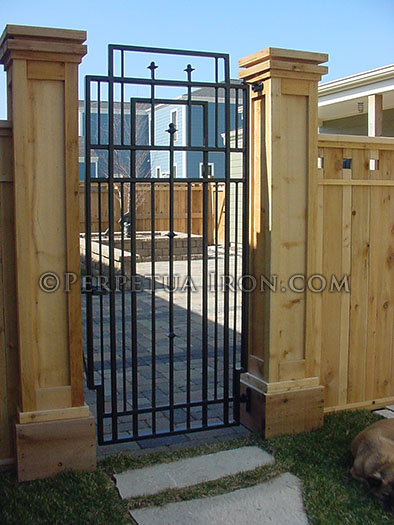 Wrought iron patio entrance gate, custom designed to complement wooden fence.