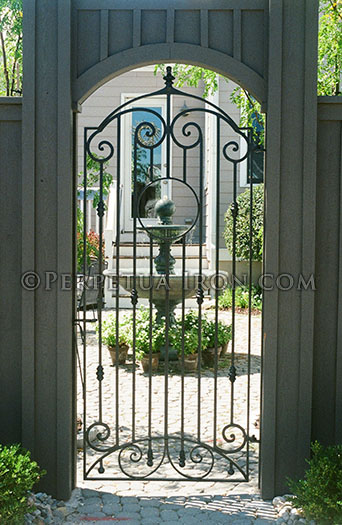 symmetrical image of a gemoetricly shaped, smooth masonry archway with an organic iron courtyard gate, custom design for client