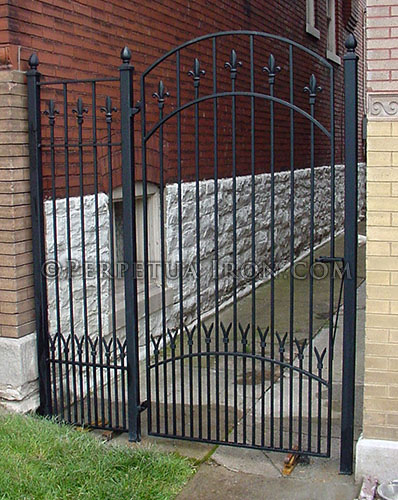 detail of custom ornamental gate for a residence showing the lower portion of the gate's tight pickets.