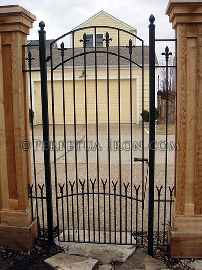 Custom iron arched gate with fleur de lis finials.
