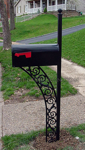 Installed mailbox with curved railing detail in a bracket that connects mailbox to ground and the post.