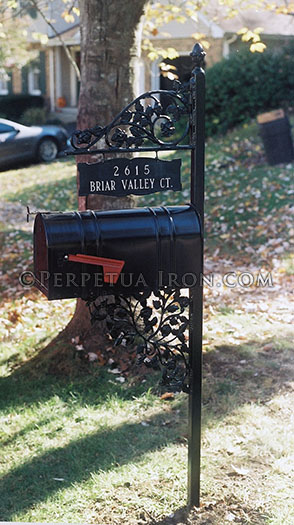 An especially old fashioned, decorative mailbox with hanging sign component.