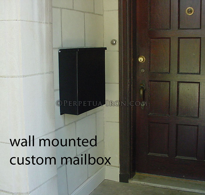 Wall ounted custom mailbox next to a dark wood front door.