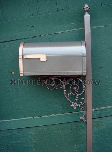 An ornamental iron mailbox post painted in bronze.