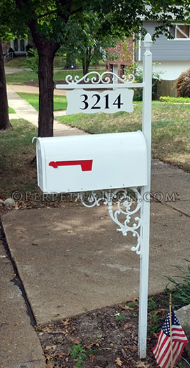 An ornamental iron mailbox post, with cast iron brackets for hanging sign.